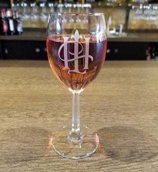 A glass of wine in a glass etched with the Hook & Ladder logo